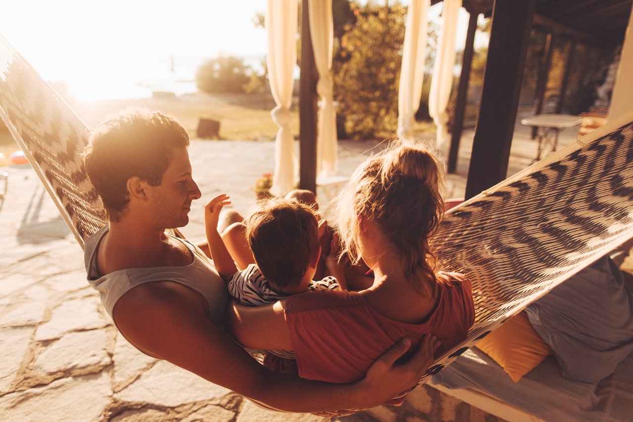 Familie sitzt in einer Hängematte.